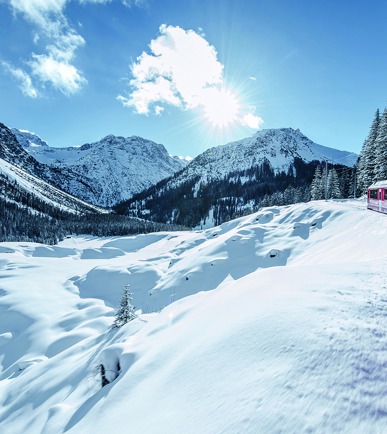 Ein Zug der Rhätischen Bahn bei Sonnenschein und Schnee